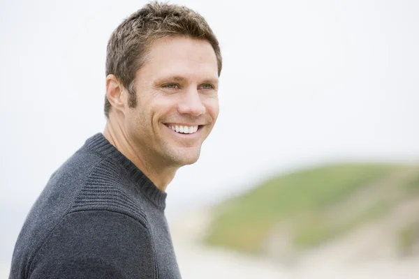 Чоловік стоїть на пляжі посміхається — стокове фото