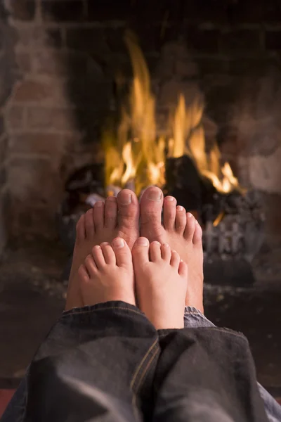 Füße von Vater und Sohn wärmen sich am Kamin — Stockfoto