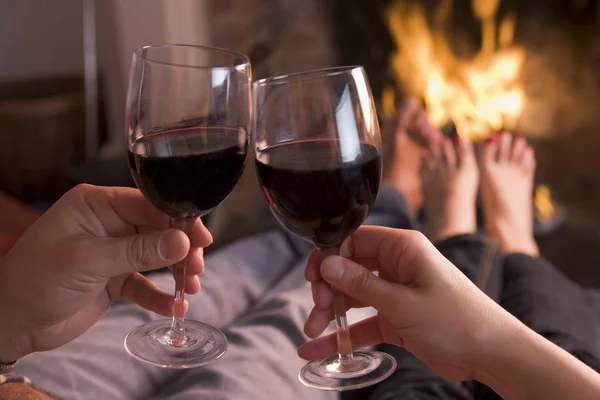 Pies de calentamiento en la chimenea con las manos sosteniendo el vino — Foto de Stock