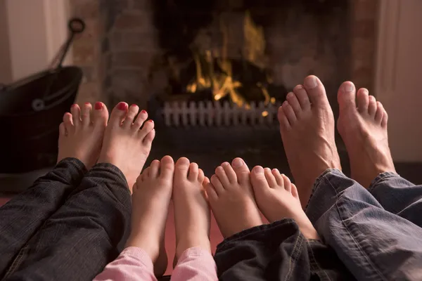 暖炉で暖まる足の家族 — ストック写真