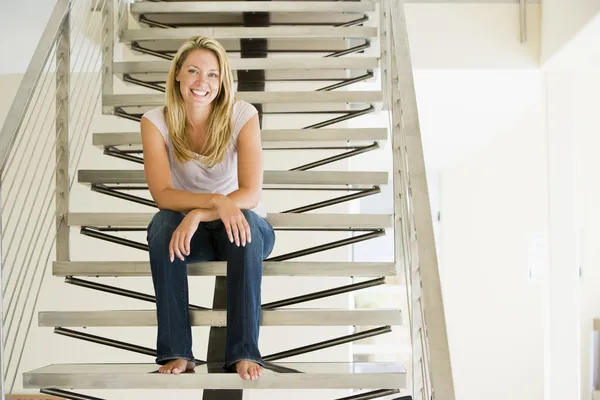 Женщина, сидящая на лестнице улыбаясь — стоковое фото