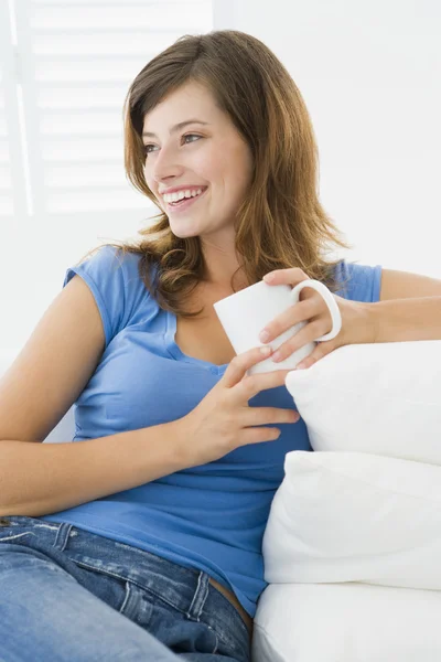 Frau im Wohnzimmer mit Kaffee lächelnd — Stockfoto