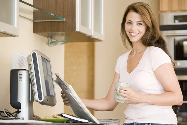 Γυναίκα Στην Κουζίνα Στον Υπολογιστή Την Εφημερίδα Και Καφέ Χαμογελώντας — Φωτογραφία Αρχείου