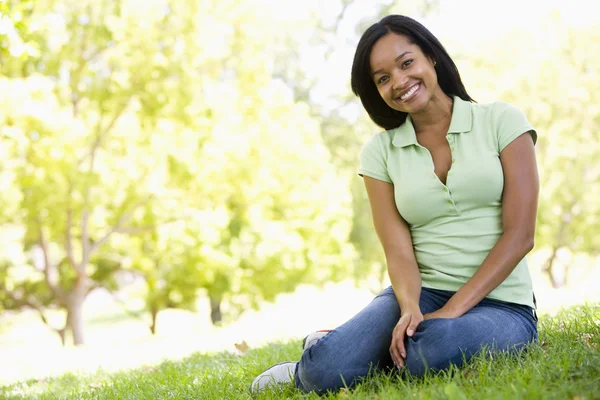 Woman sitting outdoors smiling — Stock Photo, Image