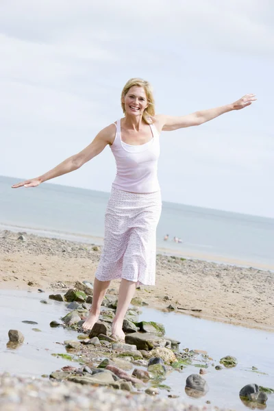 Kvinnan promenader på stranden väg leende — Stockfoto