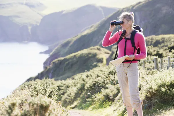 Kobieta na cliffside ścieżka za pomocą lornetki — Zdjęcie stockowe