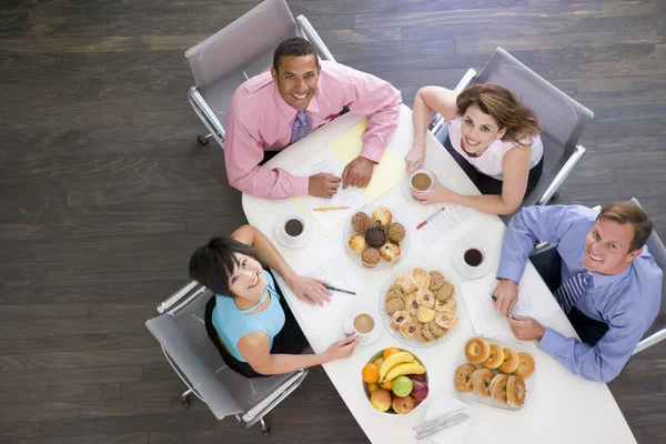 四个商人在会议桌与早餐微笑 — 图库照片