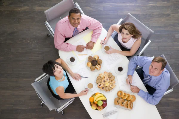 四个商人在会议桌与早餐微笑 — 图库照片