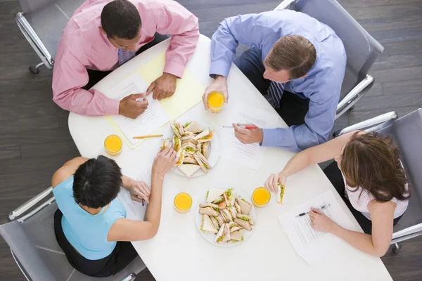 Vier ondernemers aan directiekamer tafel met broodjes — Stockfoto