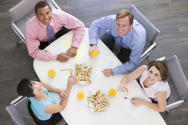 Vier Ondernemers Aan Directiekamer Tafel Met Broodjes Glimlachen — Stockfoto
