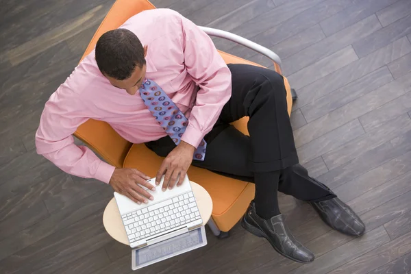 Businessman sitting indoors with laptop — Stock Photo, Image