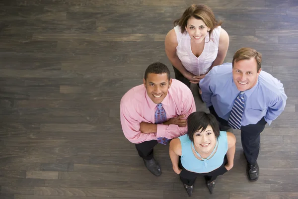 Négy üzletemberek, állandó, zárt térben mosolyogva — Stock Fotó