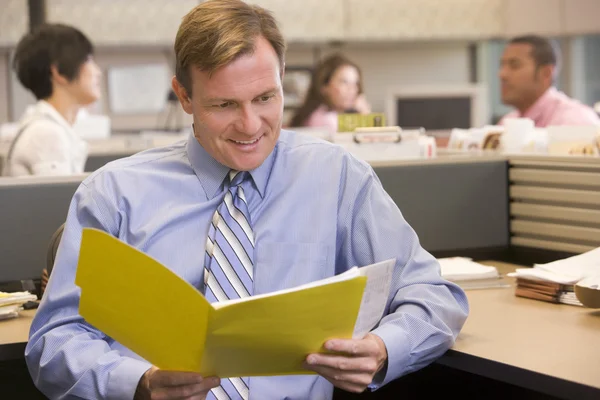 Uomo d'affari in cubicolo con cartella sorridente — Foto Stock