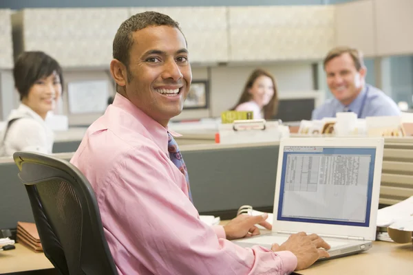 Uomo d'affari in cubicolo con computer portatile e sorridente — Foto Stock