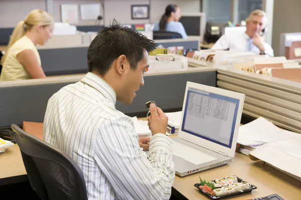 寿司を食べることのラップトップのキュービクルのビジネスマン — ストック写真