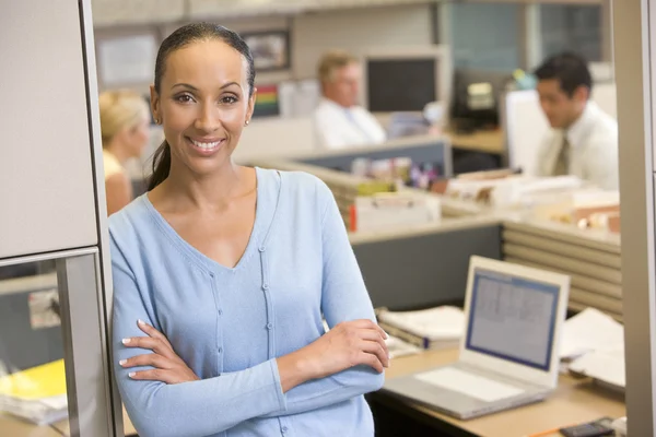 Businesswoman standing in cubicle smiling — Stock Photo, Image