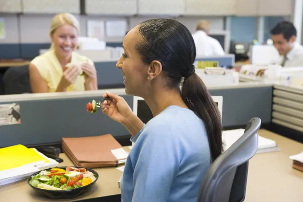 Affärskvinna i skåp äta sallad och ler — Stockfoto
