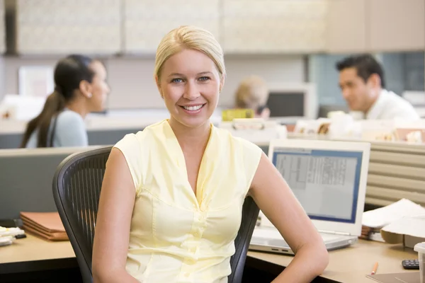 Businesswoman in cubicle smiling — Stock Photo, Image