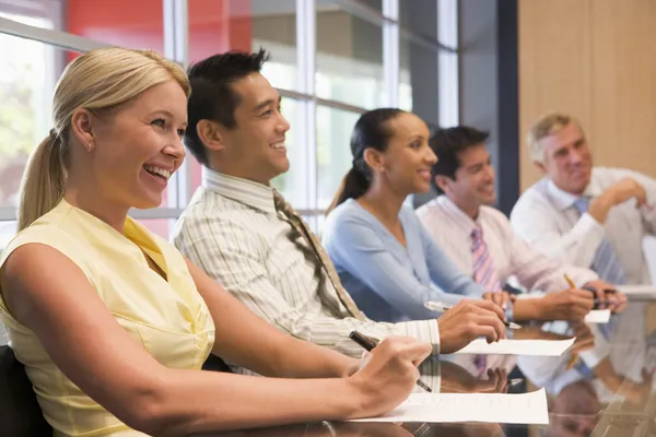 Vijf ondernemers op de directiekamer tabel glimlachen — Stockfoto