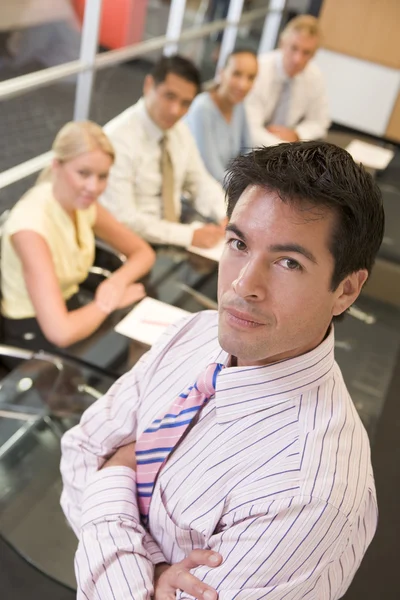 Businessman with four businesspeople at boardroom table in backg — Stock Photo, Image