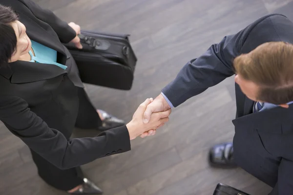 Zwei Geschäftsleute, die drinnen stehen und Hände schütteln — Stockfoto