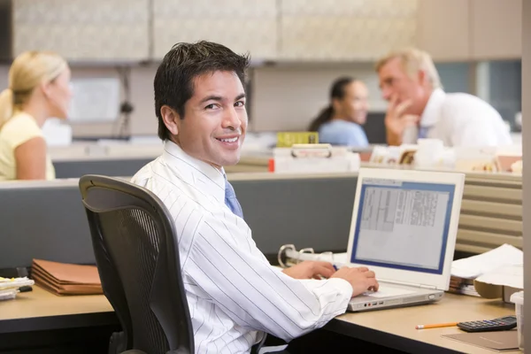 Uomo d'affari in cubicolo con laptop sorridente — Foto Stock