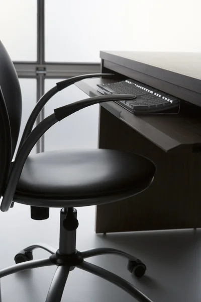 Silla de oficina vacía y escritorio con teclado de computadora —  Fotos de Stock