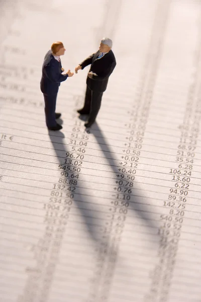 Figurines de deux hommes d'affaires serrant la main sur un journal financier — Photo