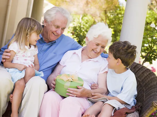 Großeltern Mit Enkeln Auf Der Terrasse Mit Geschenk Lächelnd — Stockfoto