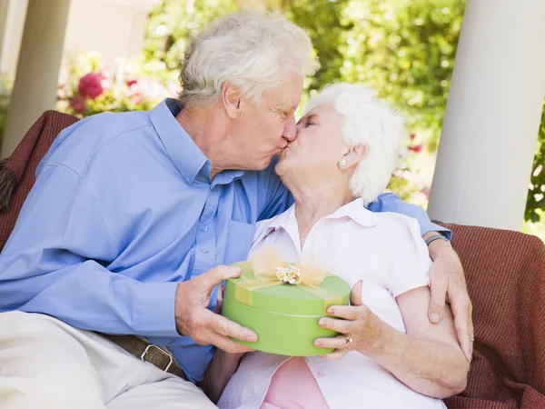 Husband giving wife gift on patio and kissing her — Stock Photo, Image
