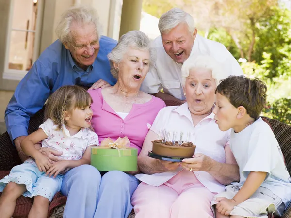 Abuelos y nietos en el patio con pastel y un regalo smili —  Fotos de Stock