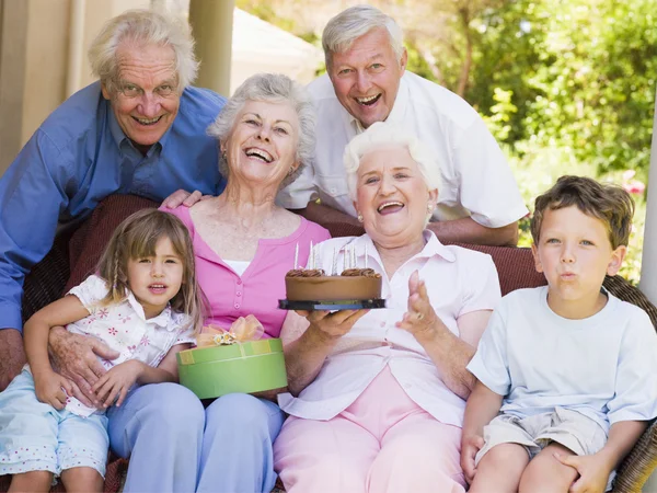 祖父母と孫ケーキ ギフトの Smili とパティオで — ストック写真