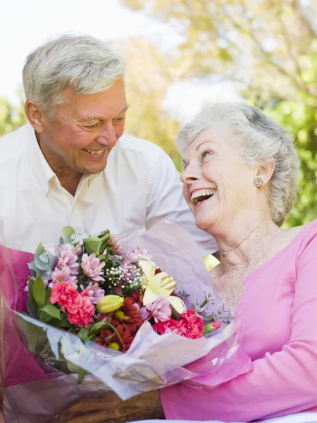 Kocam dışarıda gülümseyen eşi çiçek vererek — Stok fotoğraf