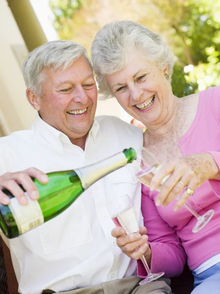 Пара в патио пьет шампанское и улыбается. — стоковое фото