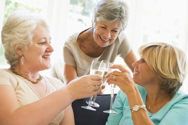 Três mulheres na sala de estar brindando champanhe e sorrindo — Fotografia de Stock