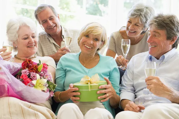 Vijf vrienden met champagne en giften in woonkamer glimlachen — Stockfoto