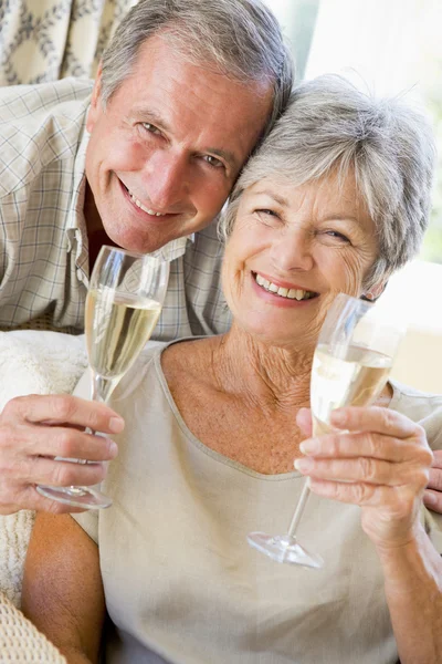 シャンパンを飲むと笑みを浮かべてのリビング ルームでのカップル — ストック写真