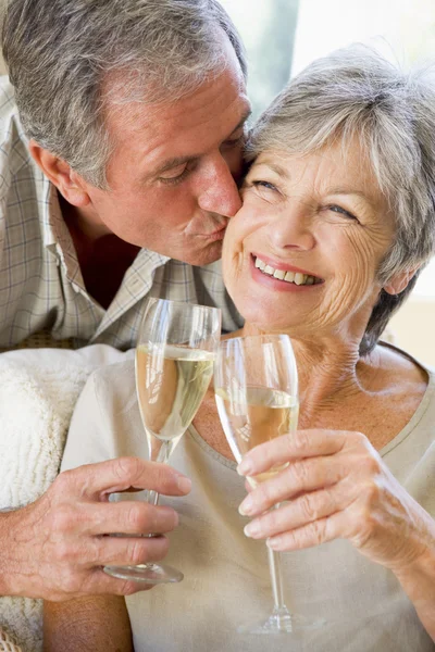 Líbání pár, v obývacím pokoji opékání šampaňské a usmívá se — Stock fotografie