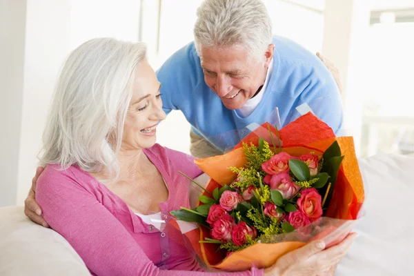 Marito dando fiori moglie e sorridente — Foto Stock