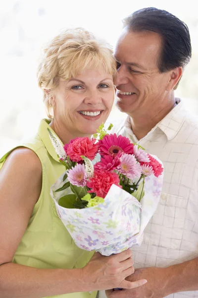 Karı ve çiçek tutan ve gülümseyerek — Stok fotoğraf