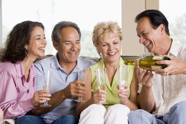 Two couples in living room drinking champagne and smiling — Stock Photo, Image