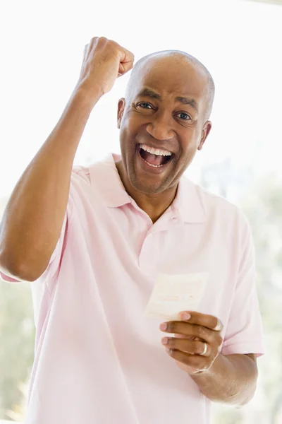 Hombre con billete de lotería ganador emocionado y sonriente —  Fotos de Stock