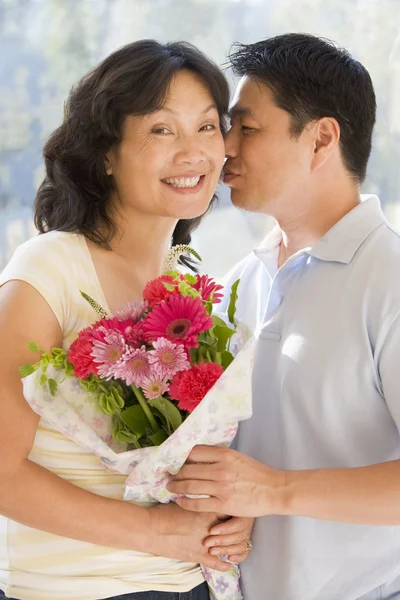 Man och hustru hålla blommor kyssar och leende — Stockfoto