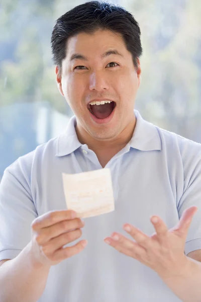 Чоловік з виграшним лотерейним квитком схвильований і усміхнений — стокове фото