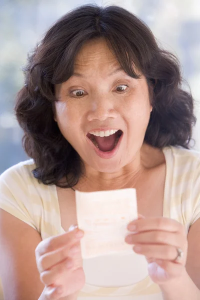 Жінка з виграшним лотерейним квитком схвильована і посміхається — стокове фото