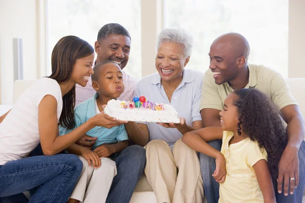 Famiglia in salotto sorridente con giovane ragazzo che soffia candele — Foto Stock