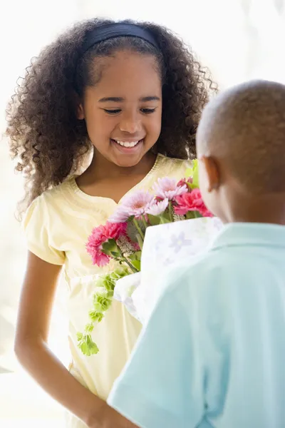 Mladý chlapec dává mladé dívce květiny a usmívá se — Stock fotografie