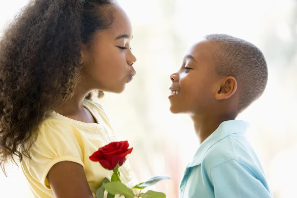 Młody chłopiec dając młoda dziewczyna, róża i uśmiechnięty — Zdjęcie stockowe