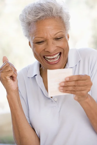 Mujer con billete de lotería ganador emocionado y sonriente —  Fotos de Stock