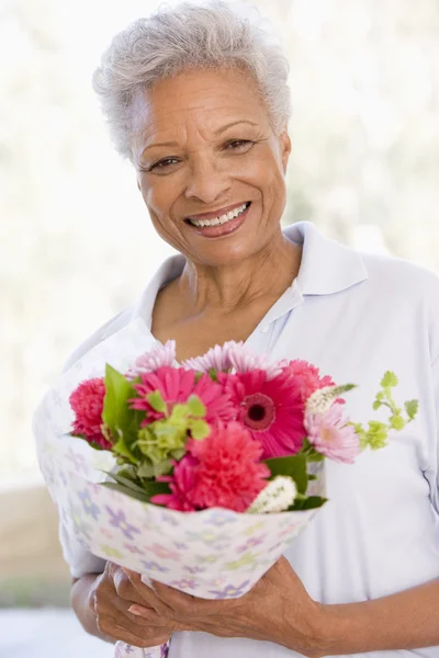 女性の花を保持していると笑みを浮かべて — ストック写真